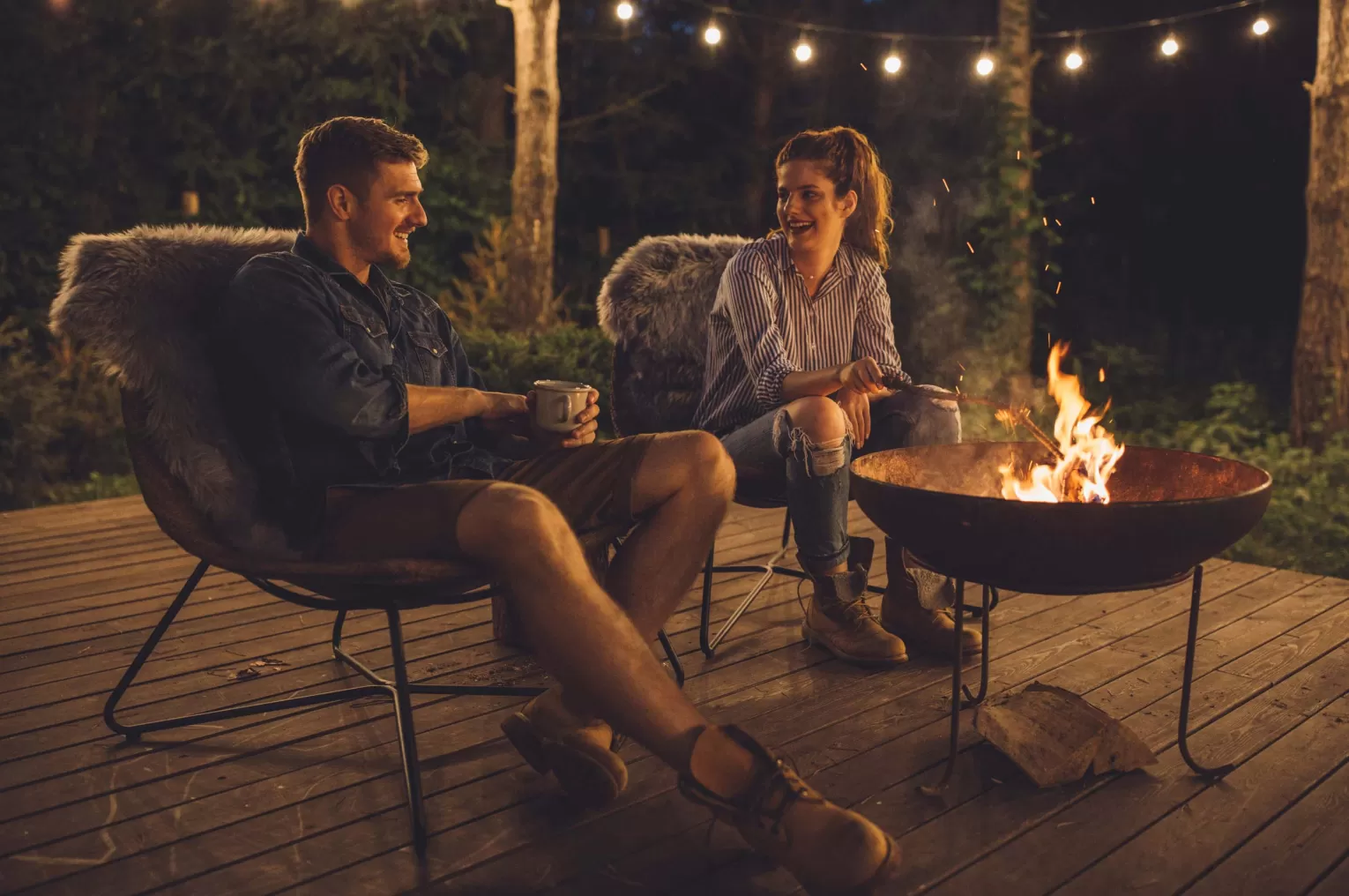 Couple enjoying a fire pit outside a glamping lodge